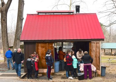 people gathered outside of a maple syrup shack